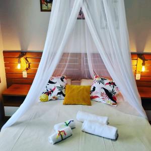 a bed with a canopy with two towels on it at Casa noites tropicais in Imbassai