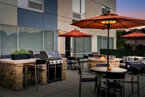 un patio esterno con tavoli, sedie e griglia di TownePlace Suites by Marriott Pittsburgh Harmarville a Harmarville