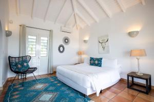 a bedroom with a white bed and a chair at Villa Madras in Les Terres Basses