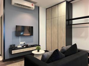 a living room with a black couch and a tv at Vista Bangi Apartment in Kajang