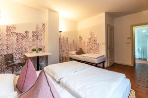 Habitación de hotel con 2 camas y mesa en Sleep In Venzone Depandance en Venzone