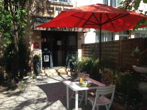 a table with a red umbrella and two chairs at Hôtel L'Eau Des Collines in Marseille