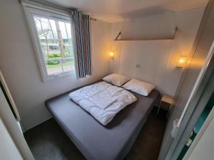 a small bed in a small room with a window at Chalet vakantiepark Kleine Belties 18 in Hardenberg