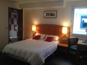 1 dormitorio con 1 cama grande y 2 almohadas rojas en initial by balladins Saint-Quentin / Gauchy, en Gauchy