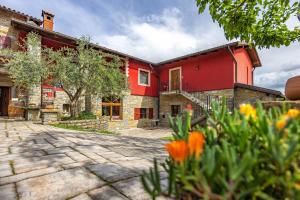 un edificio rojo con flores delante en TouristFarm - apartments "RED FAIRYTALE", en Marezige