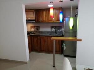 a kitchen with wooden cabinets and a table and a refrigerator at Lindo Apartamento en alquiler in Rionegro