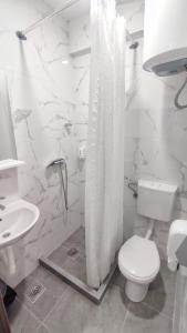 a white bathroom with a toilet and a shower curtain at Jazina Hotel in Trebinje