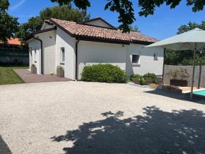 una casa bianca con un ombrello davanti di Cosy and lovely villa Trosti with a POOL a Svetvinčenat (Sanvincenti)