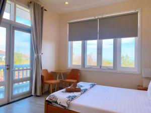 een slaapkamer met een bed en 2 stoelen en een raam bij Villa Sea Link - Phan Thiết in Phan Thiet
