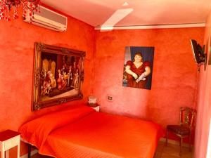 een rode slaapkamer met 2 bedden en een schilderij aan de muur bij tre case in Gambassi Terme
