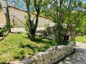 a stone wall with two trees next to a house at CASA MUPI in SantʼEufemia a Maiella