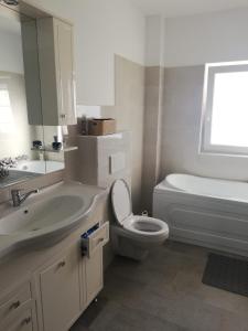 a bathroom with a sink and a toilet and a tub at Casa luminoasa cu parcare gratuita la proprietate in Dumbrăviţa