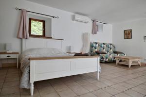 a white bedroom with a bed and a couch at Le Gauliat in Espartignac