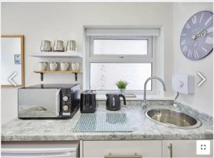 Una encimera de cocina con un microondas y un fregadero. en The Guest Place, en Redcar 1 foto más