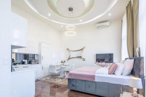 a white bedroom with a bed and a kitchen at Opera Luxury Studio Apartment in Budapest