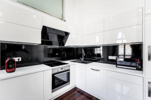 a white kitchen with white cabinets and black appliances at Opera Luxury Studio Apartment in Budapest