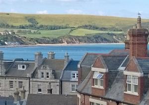 a view of a town with houses and the ocean at Upper Nestleton Maisonette in Swanage