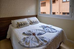 a bedroom with a bed with white sheets and a window at Apartamento Villaggio Del Veneto 1 dorm by Achei in Canela
