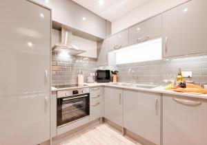 uma cozinha com armários brancos e um lavatório em Victoria Sands em Swanage
