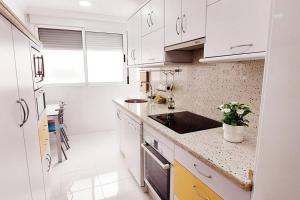 uma cozinha branca com armários brancos e um lavatório em Acogedor piso cerca de la playa em Ceuta