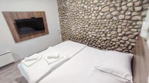 a bedroom with a bed with a stone wall at Jazina Hotel in Trebinje