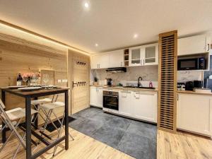 a kitchen with white cabinets and a table with chairs at Évasion Parfaite in Chamonix