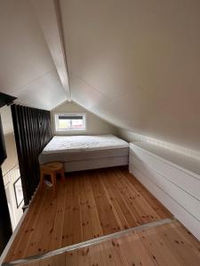 a small bedroom with a bed and a wooden floor at Midnattsol rom og hytter in Bleik