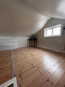 um quarto vazio com piso em madeira e uma janela em Midnattsol rom og hytter em Bleik