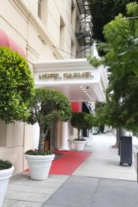 a hotel entrance with potted trees on a sidewalk at Hotel Carmel Santa Monica in Los Angeles
