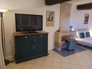 a living room with a tv on a cabinet and a fireplace at Chez Catharina Oldtimer B&B in Levoncourt