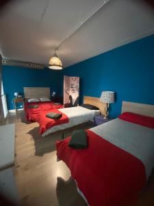 um quarto com 2 camas com lençóis vermelhos e paredes azuis em Las Tontunas em Madrid