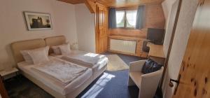 ein Schlafzimmer mit einem Bett, einem Stuhl und einem TV in der Unterkunft Gasthof Küssaburg in Küssaberg