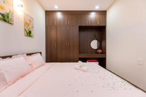 a bedroom with a white bed with a wooden cabinet at Căn hộ OASKY 2 phòng ngủ view biển ngay quảng trường Vũng Tàu in Vung Tau