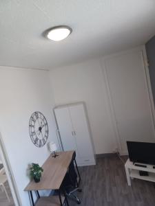 een kamer met een bureau en een klok aan de muur bij Le Carnot Proche gare et IUT Chez Adrien in Saint-Quentin