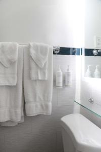 Baño blanco con toallas blancas y lavamanos en Hotel Carmel Santa Monica, en Los Ángeles