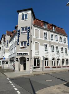a large white building on the corner of a street at Hotel Nordig free parking in Flensburg