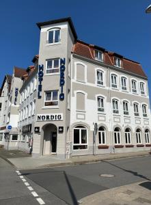 a large white building on the corner of a street at Hotel Nordig in Flensburg