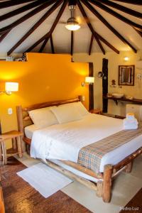 a bedroom with a large bed with a yellow wall at Pousada Villa Luna in Penedo
