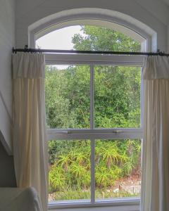una ventana con una cortina abierta en una habitación en Knysna River View Apartment, en Knysna