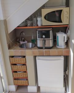 una pequeña cocina con microondas y fregadero en Knysna River View Apartment, en Knysna