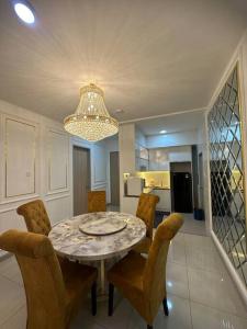 a dining room table with chairs and a chandelier at 4 Bedroom SeaView Ladang Tanjung Apartment - Ayla Homestay in Kuala Terengganu