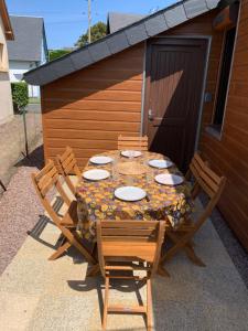 einen Tisch und Stühle auf einer Terrasse in der Unterkunft Chaleureux chalet en bord de mer in Merville-Franceville-Plage