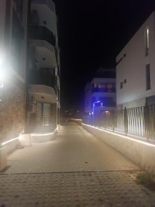 eine leere Straße in der Nacht mit Gebäuden und Lichtern in der Unterkunft Skarabey Park Apartment Sarafovo in Burgas City
