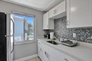 eine Küche mit weißen Schränken, einem Waschbecken und einem Fenster in der Unterkunft Oasis by Las Olas Lux Getaway in Fort Lauderdale