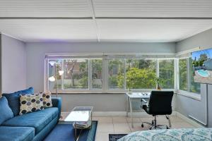 ein Wohnzimmer mit einem blauen Sofa und einem Schreibtisch in der Unterkunft Oasis by Las Olas Lux Getaway in Fort Lauderdale