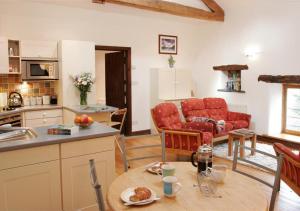 een keuken en een woonkamer met rode stoelen en een tafel bij Dale End Barn in Grasmere
