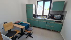 a kitchen with green cabinets and a table and a tv at Pomiculturii Residence 4 in Timişoara