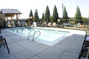a large swimming pool with chairs and a fence at TownePlace Suites Redding in Redding