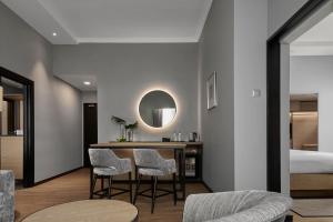 AC Hotel by Marriott Penang في بايان ليباس: غرفة معيشة مع طاولة وكراسي وسرير