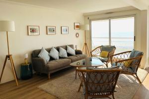 sala de estar con sofá, sillas y mesa en Appart T4 lumineux avec terrasse vue mer, en Le Touquet-Paris-Plage